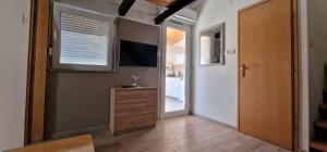 a hallway with a television and a dresser and a door at Apartmani Dutković in Vrboska