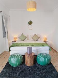 a bedroom with a bed with two green pillows at Riad L'Arganier in Marrakech