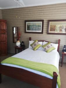 een slaapkamer met een groot bed met groene lakens en kussens bij Blood River Museum Guesthouse in Dundee