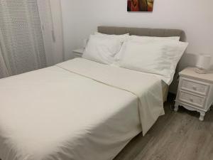 uma cama com lençóis brancos e almofadas ao lado de uma mesa de cabeceira em VAUMAR APARTMENT - SEA VIEW em Portimão