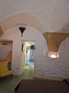 Habitación con pared de piedra, cama y silla amarilla. en CASA STELLA, en Lecce