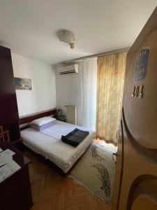 a small bedroom with a bed and a window at Vila Grinka M in Zaječar