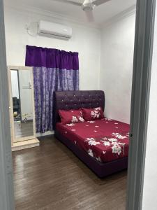 Cama en habitación con cortina púrpura en DHIA HOMESTAY en Machang