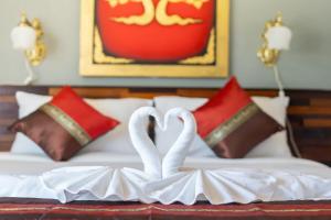 Dos cisnes blancos haciendo forma de corazón en una cama en Memory 2 en Patong Beach