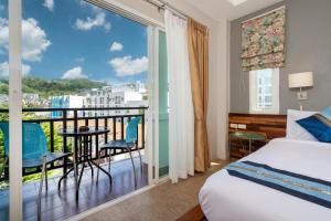 Un dormitorio con una cama y un balcón con vistas. en SawasdeeCiao Patong Guesthouse, en Patong Beach