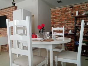 una mesa y sillas blancas en una habitación con una pared de ladrillo en Sava Lux Apartment & Room, en Prijedor