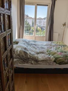 Bett in einem Schlafzimmer mit Fenster in der Unterkunft Appartement in Franconville