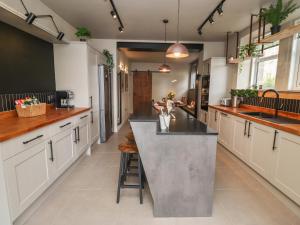 a large kitchen with white cabinets and a large island at Glencoe House in Wooler