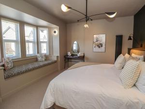 a bedroom with a large white bed and windows at Glencoe House in Wooler