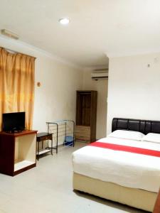 a bedroom with a bed and a desk and a television at Kenangan Inn in Pantai Cenang