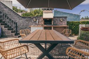 a wooden table with chairs and an umbrella at Casa do Riacho in Nordeste