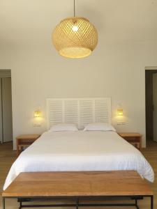 Un dormitorio con una gran cama blanca y una lámpara de araña. en Relais De Mantadia en Andasibe