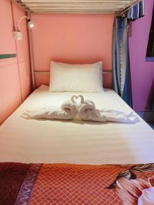 two towelsrendered to look like swans sitting on a bed at DownTown Backpackers Hostel in Luang Prabang