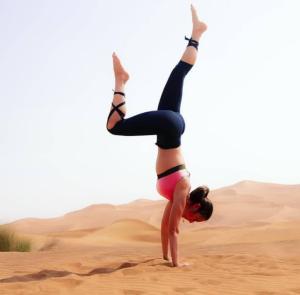 a woman doing a handstand in the desert at Enjoy Luxury Camp in Merzouga