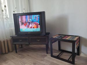 een televisie zittend op een tafel met een kruk bij Апартаменты Гоголя 46 in Karagandy