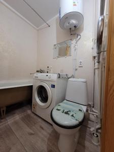 een badkamer met een toilet en een wasmachine bij Апартаменты Гоголя 46 in Karagandy