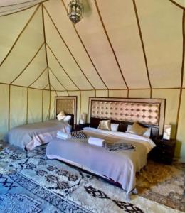 a bedroom with two beds in a tent at Enjoy Luxury Camp in Merzouga