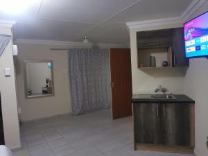 - un salon avec un lavabo et une télévision dans l'établissement Phindulo Bed and Breakfast - No Loadshedding, Smart TVs & unlimited free fibre wifi, à Krugersdorp