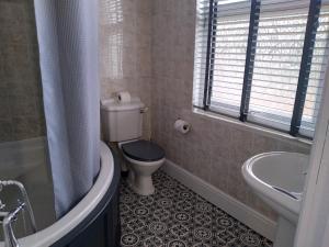 a bathroom with a toilet and a tub and a sink at Wentvale in Knottingly