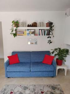- un canapé bleu dans le salon avec des oreillers rouges dans l'établissement Casa Giuditta, à Civezzano