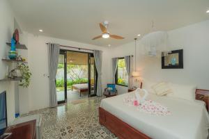 1 dormitorio con 1 cama blanca grande y ventilador de techo en An Bang Garden Beach Homestay, en Hoi An