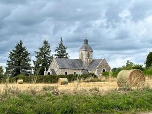 Una antigua iglesia de piedra con una torre en un campo en Les Sapins, en Beaumesnil