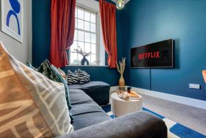 ein blaues Wohnzimmer mit 2 Sofas und einem TV in der Unterkunft 2 Bed Stunning Chic Apartment, Central Gloucester, With Parking, Sleeps 6 - By Blue Puffin Stays in Gloucester