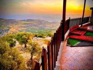 a bed on a balcony with a view of the mountains at منتجع وشالية السفينة الريفي in Ajloun