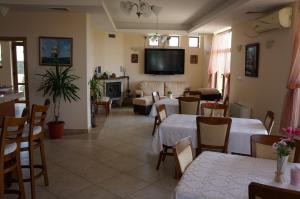 a living room with tables and chairs and a tv at Guest House Golden Flake 4km from Bolata beach in Bŭlgarevo