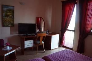 a bedroom with a bed and a desk with a television at Guest House Golden Flake 4km from Bolata beach in Bŭlgarevo