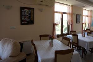 a dining room with white tables and chairs and a window at Guest House Golden Flake 4km from Bolata beach in Bŭlgarevo