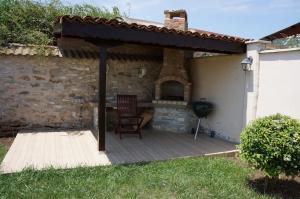 a patio with a fireplace and a chair on a deck at Guest House Golden Flake 4km from Bolata beach in Bŭlgarevo