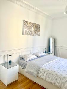 1 dormitorio blanco con 1 cama y una pintura en la pared en 15 min de Paris en train de Gare du Nord et 10 min Stade de France, en Enghien-les-Bains