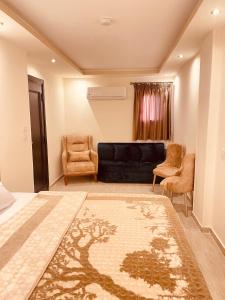 El Mansour Hotel Apartmen 92 في المنصورة: غرفة معيشة مع أريكة سوداء وكراسي