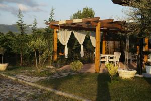 pérgola de madera con mesa y sillas en un patio en NATYRA E ISHULLIT, Lezhe ,Ishull Shengjin, Lezhe, Alessio, Shengjin en Ishull-Shëngjini