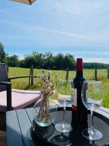 a table with two wine glasses and a bottle of wine at Logement insolite : La Ruche Verte in Monts-sur-Guesnes