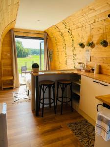 a kitchen with a counter and stools in a room at Logement insolite : La Ruche Verte in Monts-sur-Guesnes