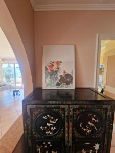 a black cabinet in a room with a painting on the wall at Grand appartement 4-8 personnes in Montreux