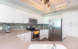 Una cocina con gabinetes blancos y un refrigerador de acero inoxidable. en Phoenix IX 1106 condo, en Orange Beach