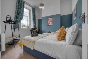 2 Bed Stunning Chic Apartment, Central Gloucester, With Parking, Sleeps 6 - By Blue Puffin Stays في غلوستر: غرفة نوم بسرير كبير بجدران زرقاء