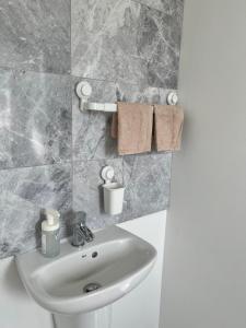 a white sink in a bathroom with marble tiles at Modern Comfy One Bed Apartment - Free Parking in Glasgow +30 photos