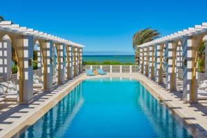 a swimming pool in a resort with the ocean in the background at Sheraton Miramar Resort El Gouna in Hurghada