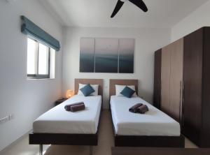 Duas camas num quarto com paredes brancas em Étoile Court Apt - homey, spacious & private patio em Mġarr