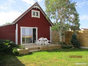 una casa roja con 2 sillas blancas en una terraza en Cottage Lillstugan proche de la Baie de Somme, en Quesnoy-le-Montant