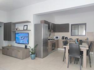 a kitchen with a dining table and a refrigerator at Étoile Court Apt - homey, spacious & private patio in Mġarr