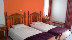 two beds in a room with orange walls at Hotel Agnanti in Ágios Konstantínos