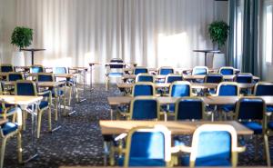 pokój pełen stołów i krzeseł z niebieskimi krzesłami w obiekcie Starby Spa, Hotell & Konferens w mieście Vadstena