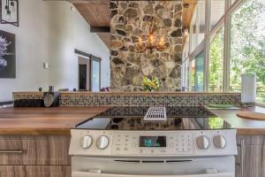 a kitchen with a stove and a stone wall at Nordika Lac St Pierre No. PERMIS CITQ: 298304 in Val des Monts