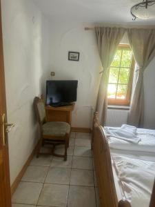 Schlafzimmer mit einem Bett, einem TV und einem Stuhl in der Unterkunft Gasthof zur Post in Siegen