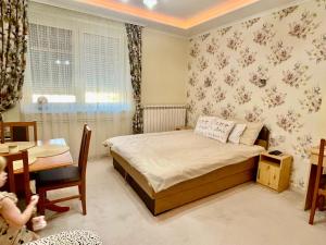 a small bedroom with a bed and a table and a child at Gita Apartman in Makó
